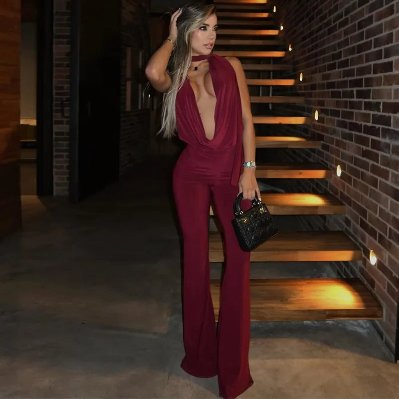 Woman in a burgundy jumpsuit standing on a staircase with brick walls.