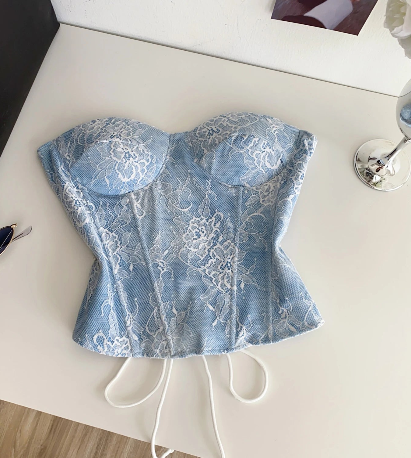 Blue lace top on a white surface with sunglasses