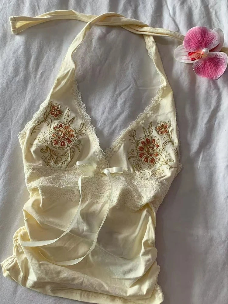 Embroidered lace top on a light background with a pink flower.