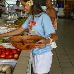 Woman holding a bowl of vegetables in a market setting