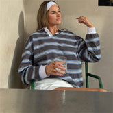 Woman wearing a striped sweater holding a glass against a neutral background