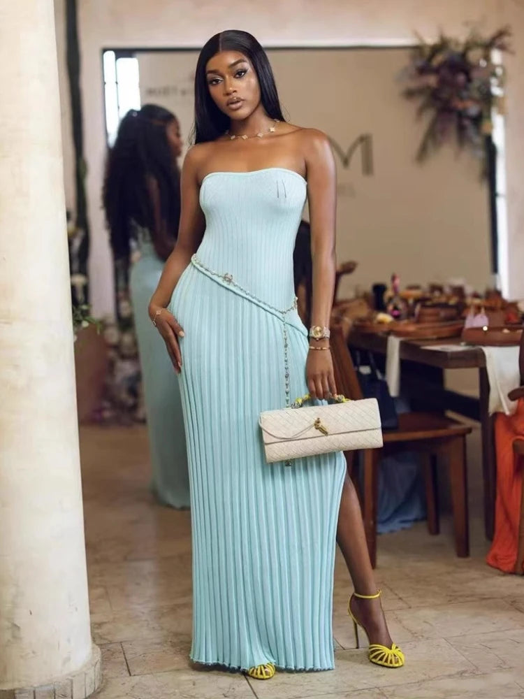 Woman in a light blue strapless dress holding a beige clutch in an indoor setting.