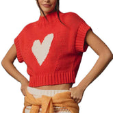 Red knitted vest with a white heart design worn by a person on a white background