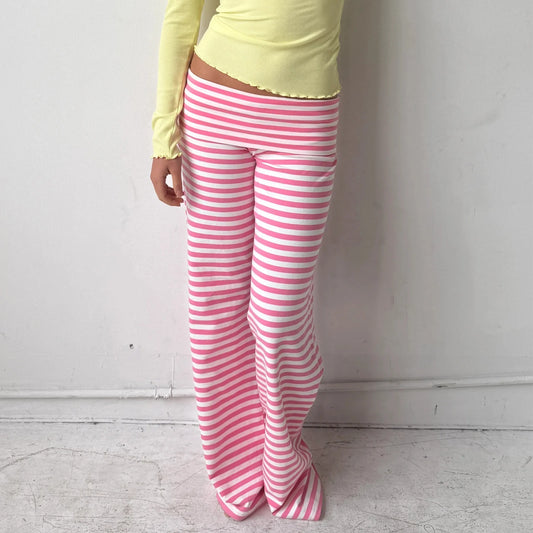 Person wearing pink and white striped pants with a yellow top against a plain background