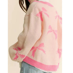 Pink sweater with butterfly pattern worn by a person on a beige background