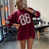 Person wearing a maroon oversized sweater with '88' design, taking a mirror selfie.