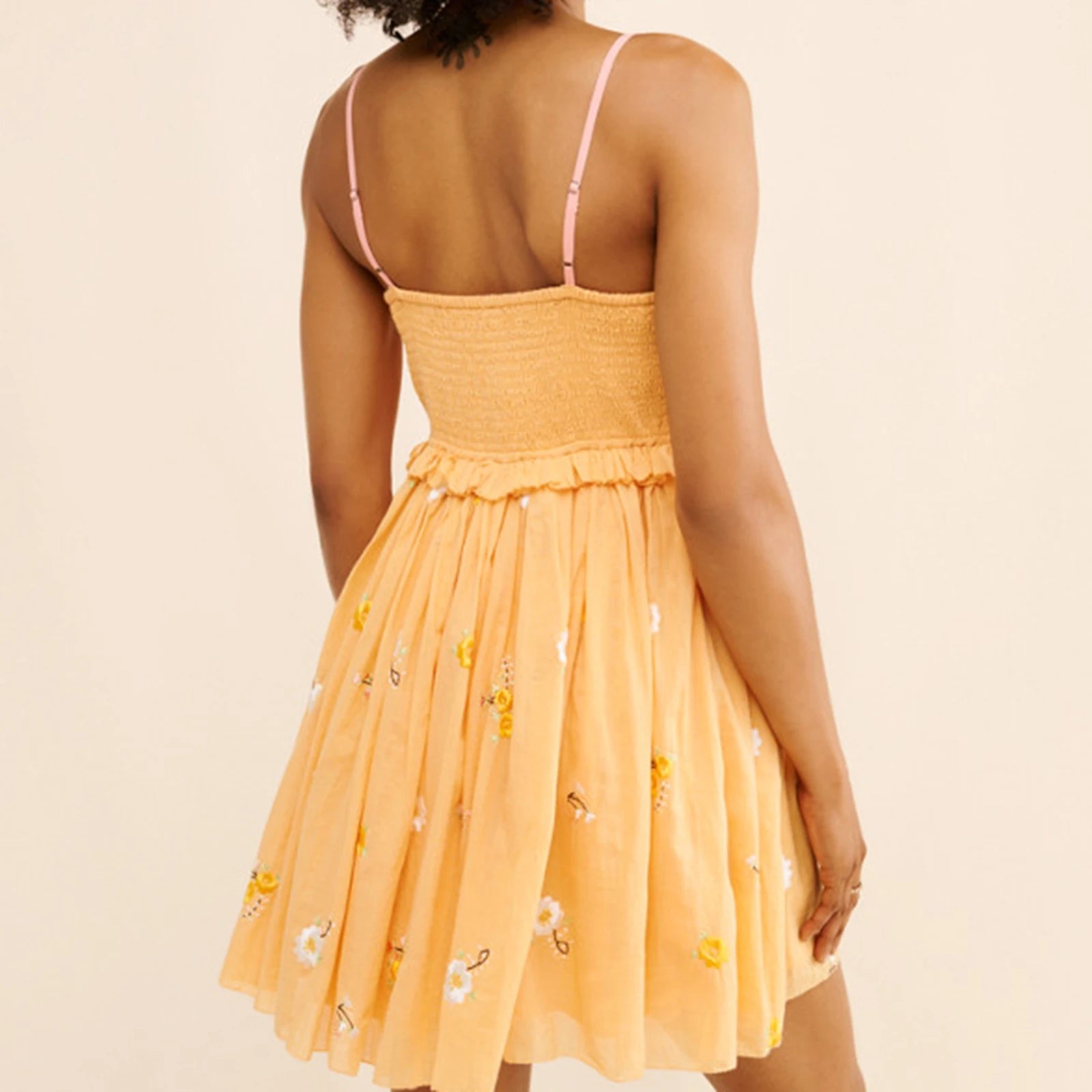Woman wearing a yellow dress with floral patterns on a beige background