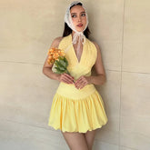 Woman in a yellow dress holding flowers against a beige wall