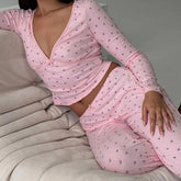 Person wearing a pink pajama set sitting on a beige couch.
