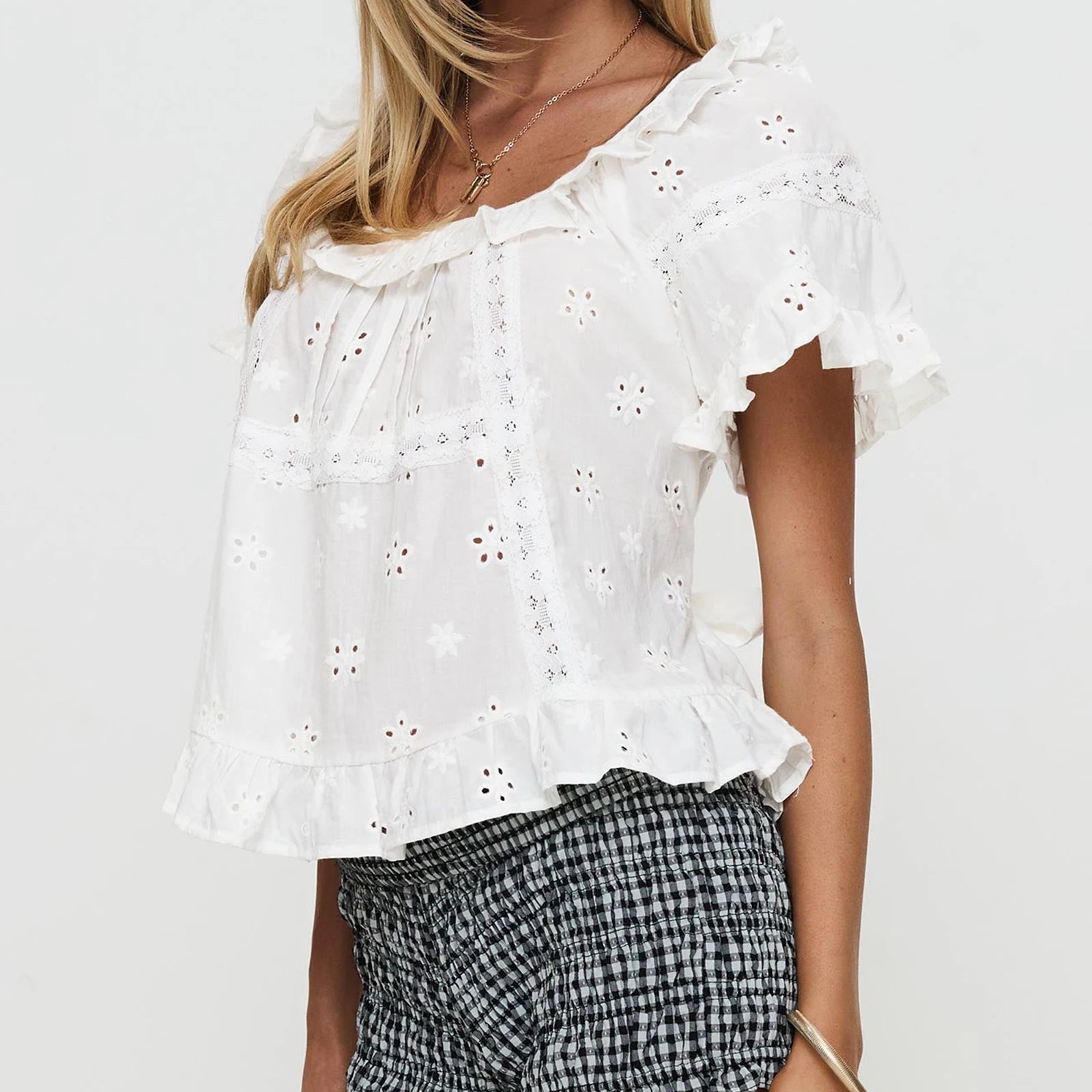 White embroidered top worn by a person - side view