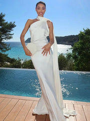 Woman in a white dress standing by a pool with a scenic background