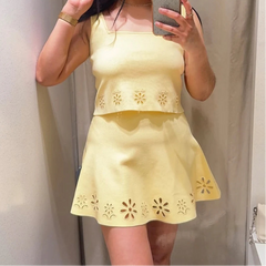 Person wearing a yellow dress with floral cutouts, taking a mirror selfie.