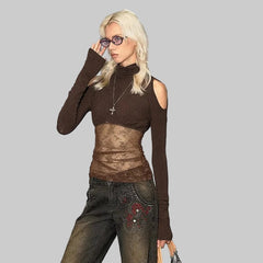 Person wearing a brown top and jeans in front of a wall with graffiti.