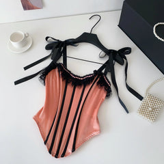 Striped swimsuit with black lace details on a hanger against a white background