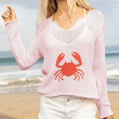 Person wearing a pink sweater with a red crab design on a beach