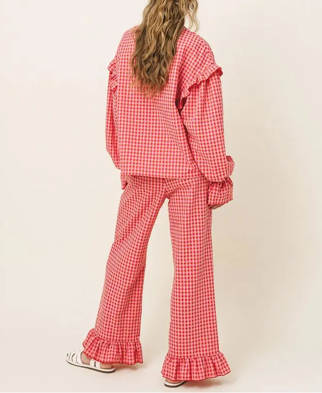 Person wearing a red checkered outfit with ruffled details on a beige background