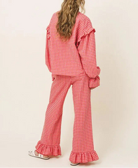 Person wearing a red checkered outfit with ruffled details on a beige background