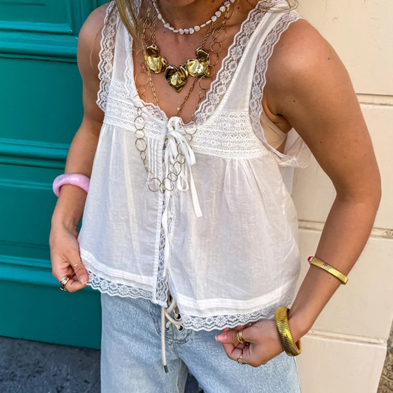 Person wearing a white lace top and light blue jeans with jewelry.