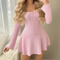 Person wearing a pink ribbed dress with long sleeves in a neutral setting