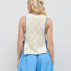 Woman wearing a white sleeveless top with blue trim and blue pants on a light gray background