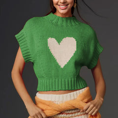 Person wearing a green knitted sweater with a heart design on a dark background