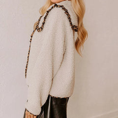 Person wearing a white textured sweater with leopard print straps