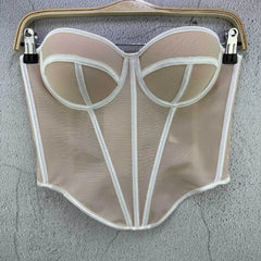Beige mesh garment on a hanger against a gray wall