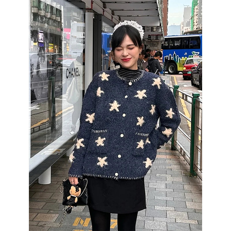 Woman wearing a navy blue sweater with white floral patterns in an urban setting.