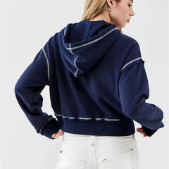 Person wearing a navy blue hoodie with white trim on a light gray background