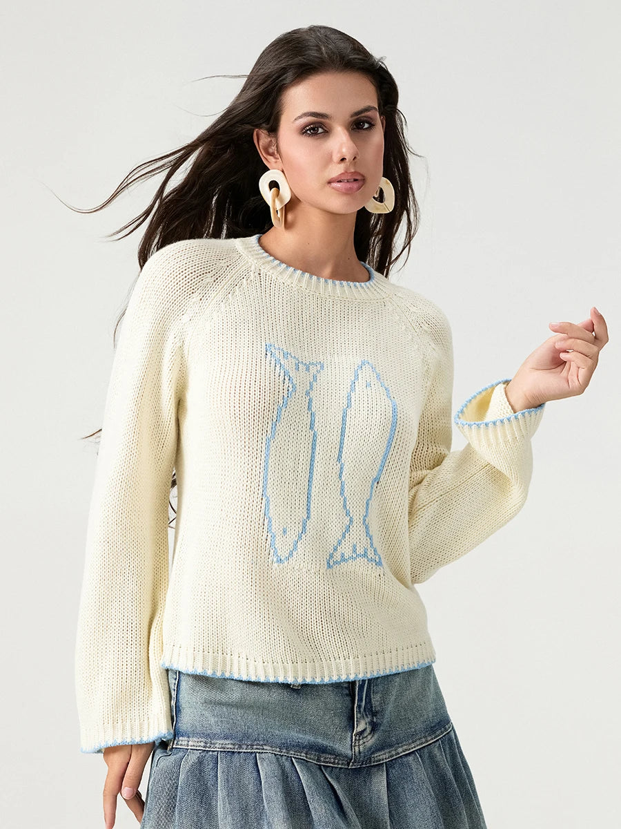 Woman wearing a cream sweater with a blue design on a white background