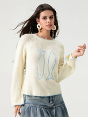 Woman wearing a cream sweater with a blue design on a white background