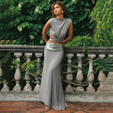 Woman in a gray dress standing in front of green foliage