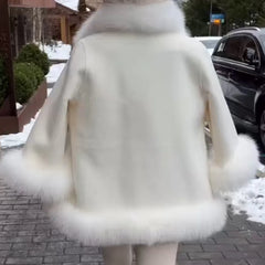 Person wearing a white fur coat in an urban setting with snow on the ground.