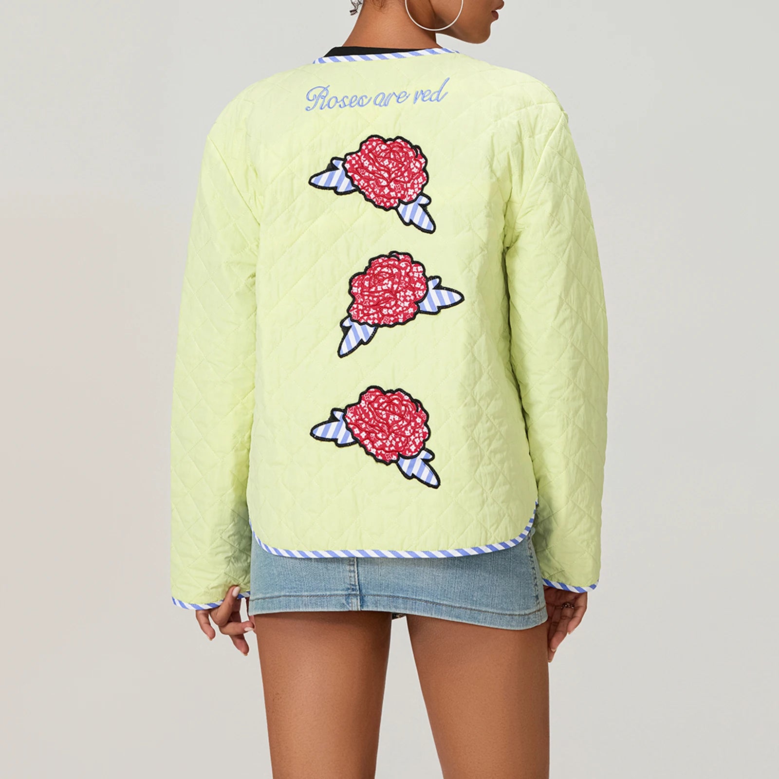 Light green quilted jacket with floral designs on the back, worn by a person.