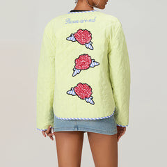 Light green quilted jacket with floral designs on the back, worn by a person.