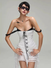 Woman wearing a white dress with black lace details on a gray background