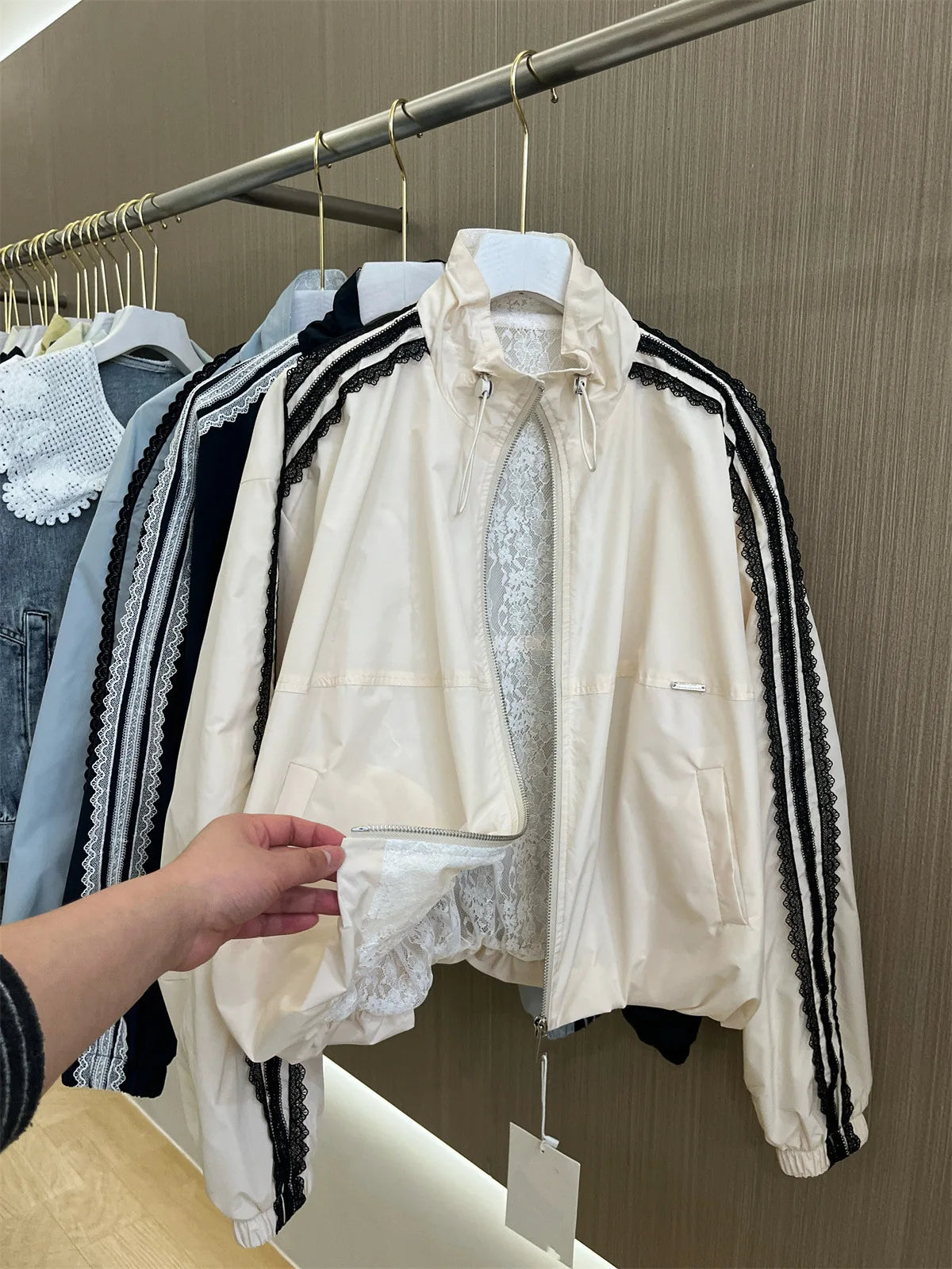 White jacket with black stripes on a hanger against a wooden wall.