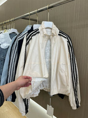 White jacket with black stripes on a hanger against a wooden wall.