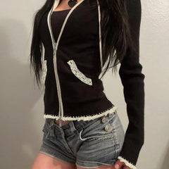 Person wearing a black zip-up hoodie with white trim and denim shorts