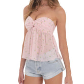 Woman wearing a pink strapless top with floral pattern and denim shorts