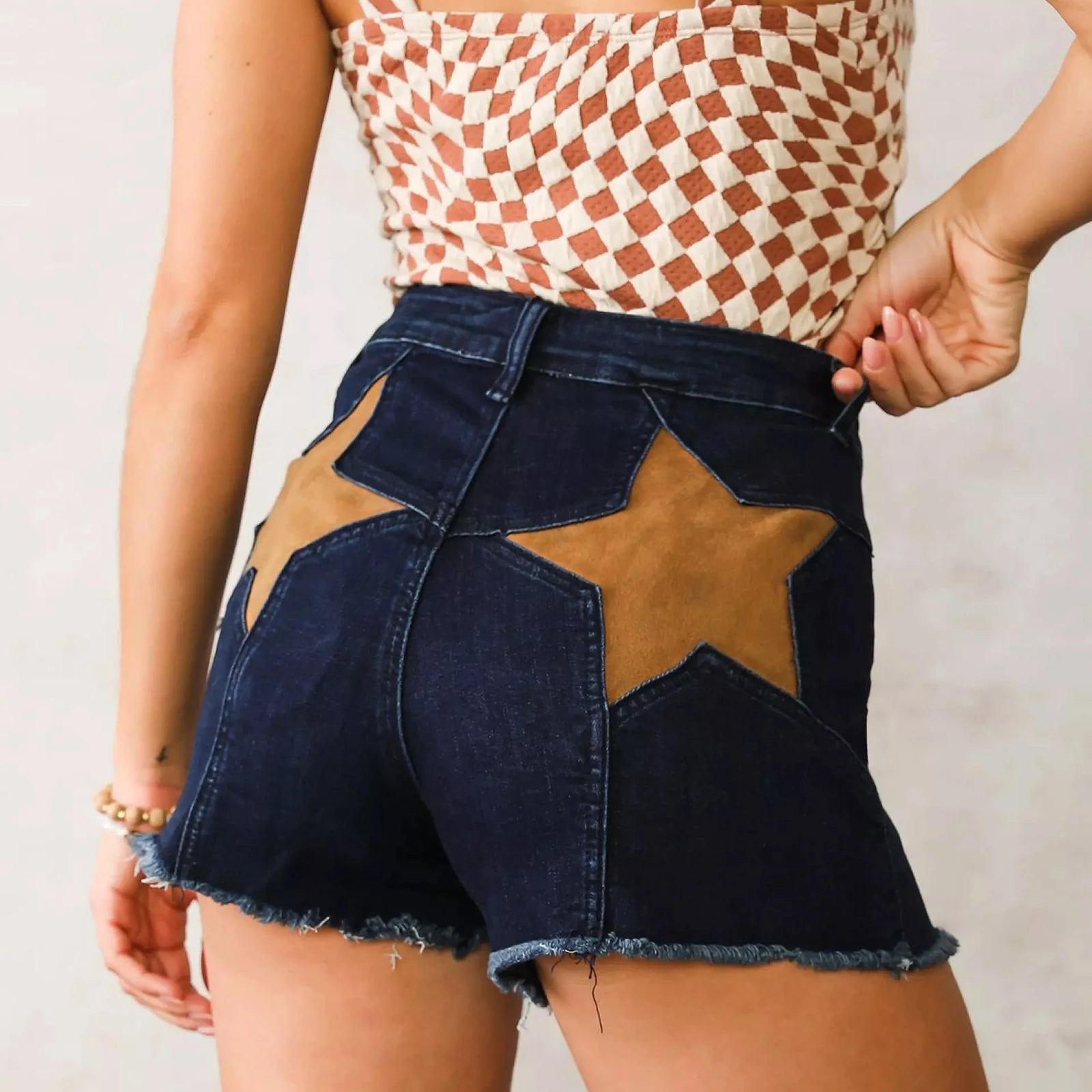 Person wearing a denim skirt with star patches and a patterned top.