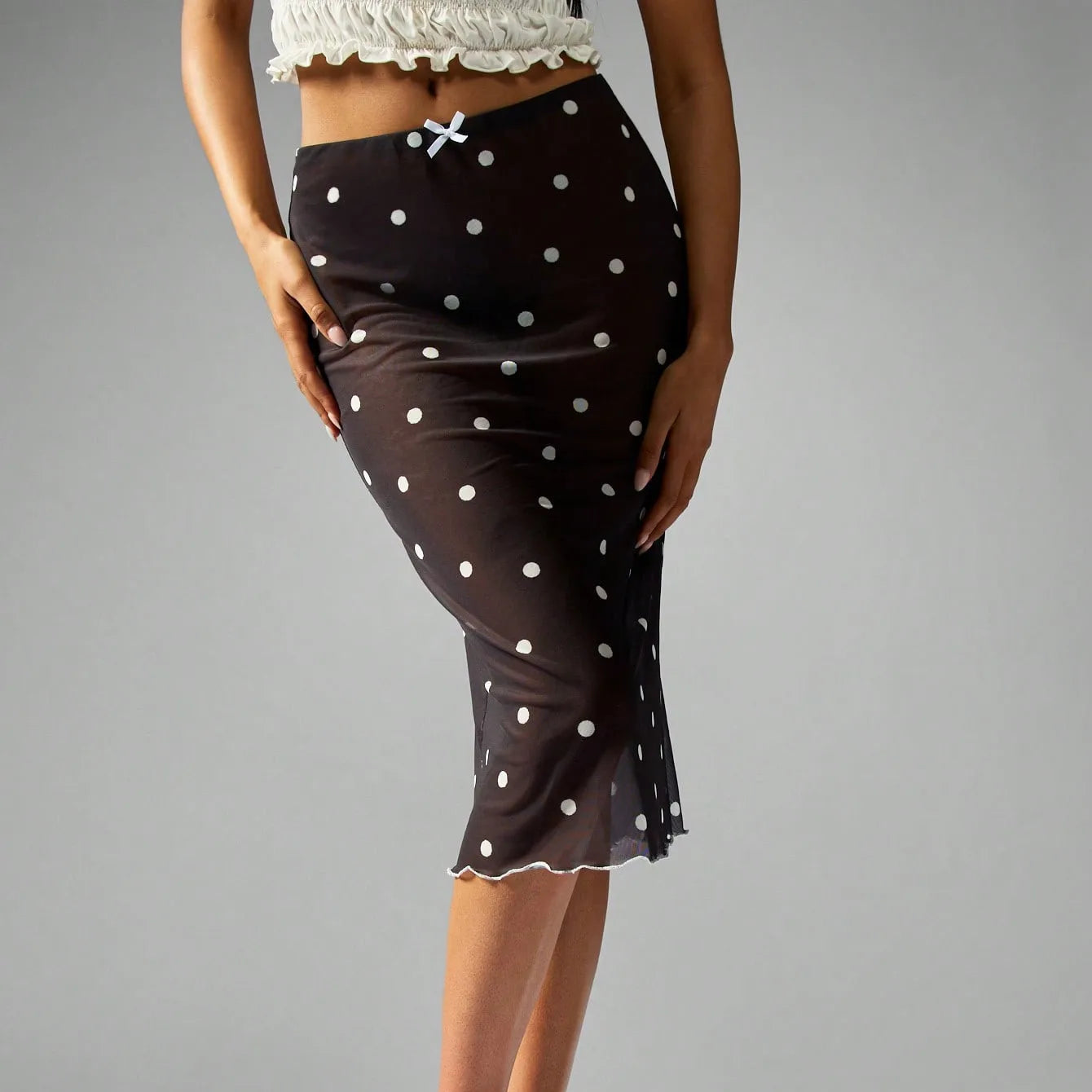 Black polka dot skirt worn by a person on a gray background