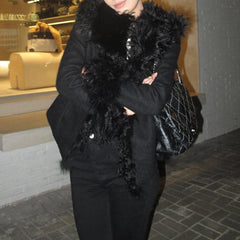 Person wearing a black coat with a fur-lined hood in an urban setting