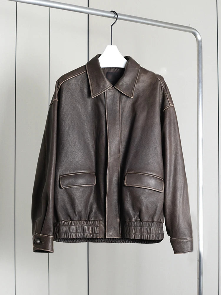 Brown leather jacket hanging on a rack against a white wall