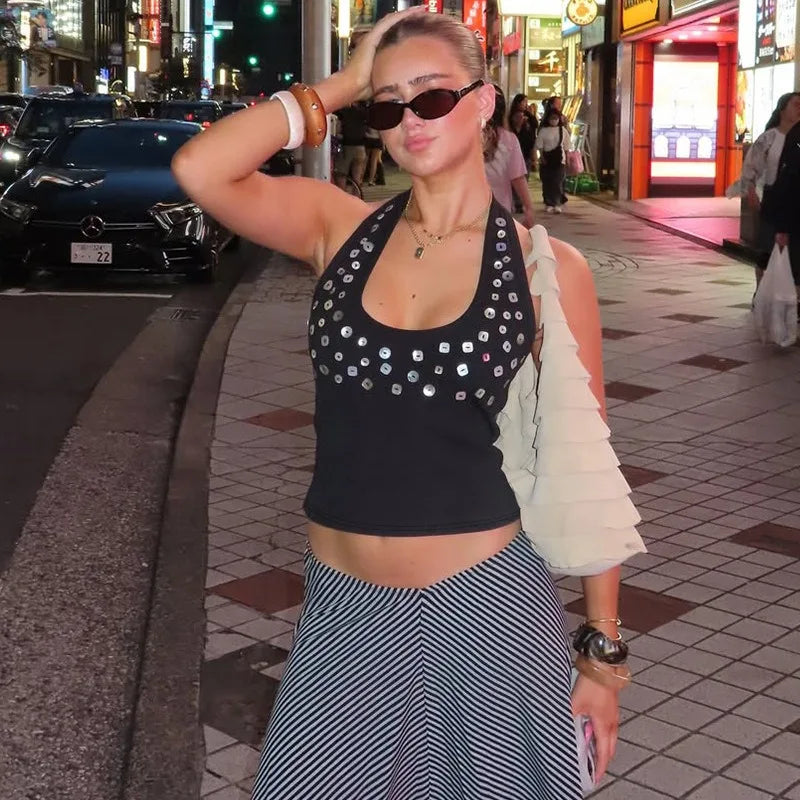 Woman in a black sequin top and striped skirt on a city street.