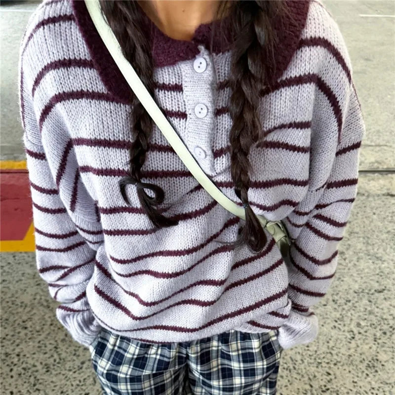 Person wearing a striped sweater with a hood and plaid pants, standing on a street.