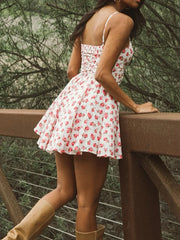 Woman wearing a white floral dress standing outdoors near a wooden railing.