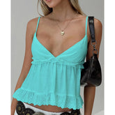 Woman wearing a turquoise top with lace details on a plain background