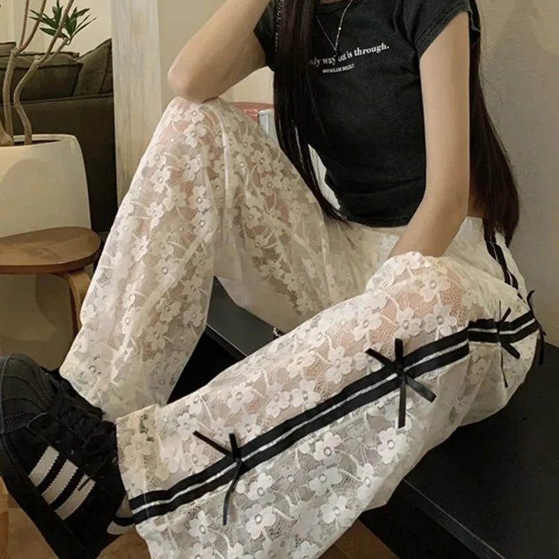 Person wearing a black t-shirt and white lace pants with black ribbons indoors.