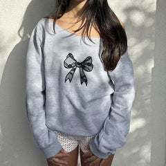 Gray sweatshirt with a black bow design worn by a person against a light background